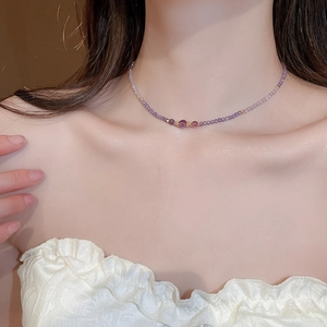 Close-up of zircon amethyst beaded necklace on neck with purple crystals and gold accents