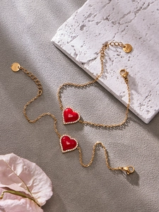Détail de bracelets en acier inoxydable doré avec breloques cœur rouge et zircons
