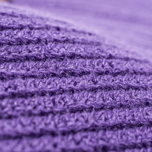 Close-up of a purple knitted beanie with thick ribbed texture and soft wool fibers