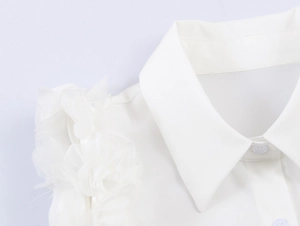 Close-up of white sleeveless shirt featuring delicate ruffled lapels and chiffon texture