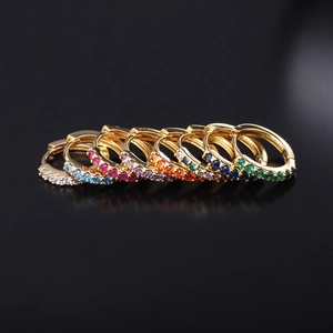 Set of nine colorful zircon gold-plated earrings on a high-reflective black surface