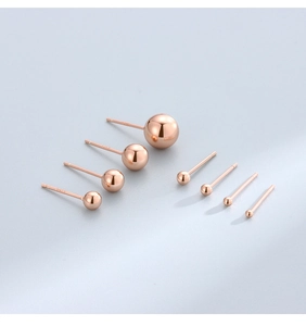 Close-up of polished rose gold S925 silver stud earrings in various sizes on grey background