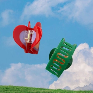 Red heart and green rectangular acetate hair claws floating over a sky and grass background