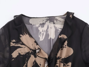 Detail of ruffled V-neckline on a black and beige abstract print chiffon dress