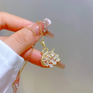 Detailed view of a gold-tone swan pendant necklace featuring sparkling crystals
