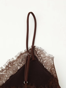 Detailed macro view of delicate lace trim and thin straps on dark brown satin camisole
