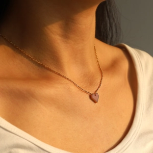 Close-up of 18k gold plated titanium necklace with a pink heart pendant on model's neck
