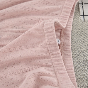 Macro shot of pink knit breathable fabric with eyelet texture and M size label