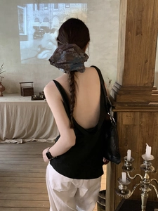 Detail of a black backless vest paired with a vintage floral scrunchie hair accessory