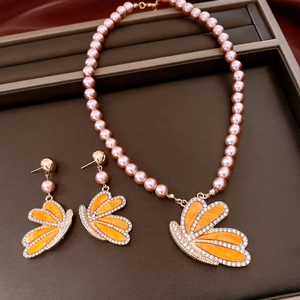 Detail of pink pearl necklace and wing pendant set with orange butterfly crystals
