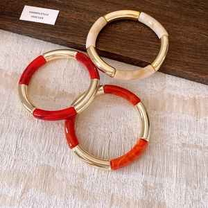 Detailed view of 3-piece acrylic and gold metal tube bracelets in marble patterns