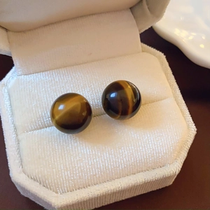 Close-up of vintage round tiger eye stud earrings in a white velvet jewelry box