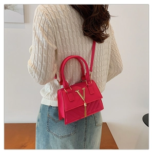 Detail of fuchsia square handbag with V-quilted texture and elegant tassel accent