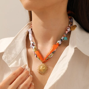 Detailed shot of an orange printed fabric necklace with a golden sun and star pendant