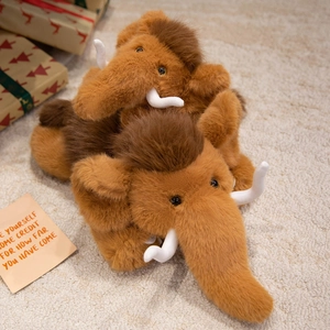 Plush mammoth stuffed animals set on soft beige carpet with holiday gift boxes