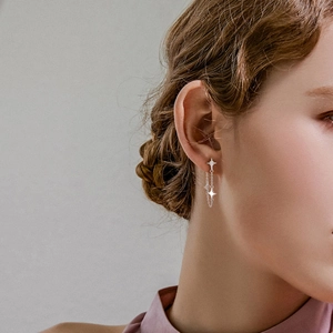 Close-up of a silver S925 star earring with fringe tassels worn by a model