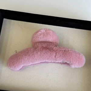 Detail view of pink plush claw clip with soft texture on a jewelry display tray