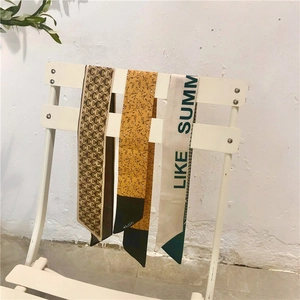 Dettaglio di foulard stretti in seta con motivi vintage, floreali e stampe in beige