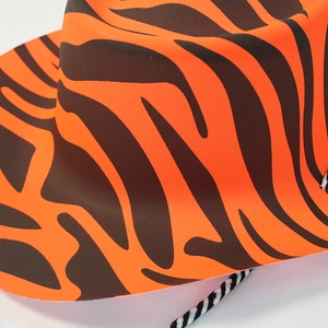 Close-up of orange and black tiger print fabric texture on a cowboy hat with woven trim
