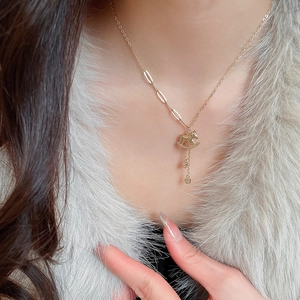 Detail of a gold rocking horse pendant necklace with round fringe on a model
