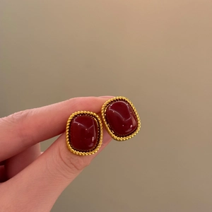 Close-up of vintage French style oval red earrings with gold woven texture border