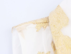 Détail du tissu en maille blanche avec broderies de plumes dorées et textures élégantes