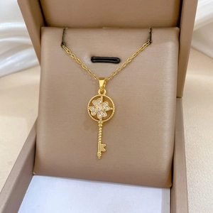 Close-up of golden spinning key necklace with sparkling clover inlay in a jewelry box