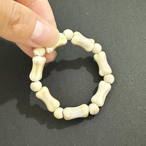 Nahaufnahme der handgefertigten Keramikperlen-Armband in Knochenform in Cremeweiß