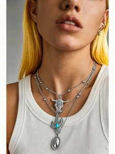 Detail of bohemian layered necklace with turquoise cactus and steer skull pendants