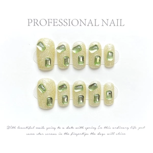 Detail of green press-on nails with sparkling gold glitter and green gemstones