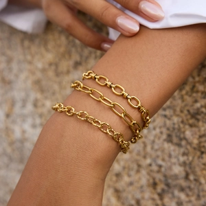 Close-up of layered 18k gold-plated titanium steel chain bracelets on a wrist