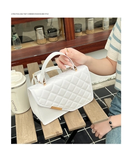 Close-up of white quilted leather texture and gold hardware on a chic crossbody bag