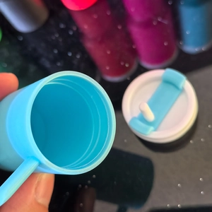 Detailed close-up of blue keychain cup showing white lid with straw and handle