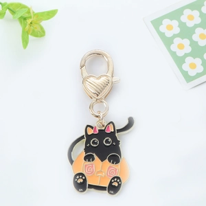 Détail du porte-clés émaillé chat noir avec fermoir coeur doré et motif de citrouille