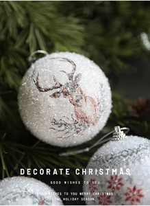 Macro shot of white matte Christmas ball with reindeer and red snowflake patterns