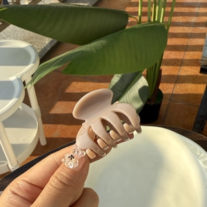 Beige pumpkin hair claw clip with transparent bear detail shown in hand