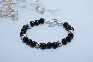 Detailed shot of beaded bracelet with black and silver beads and cross pendant