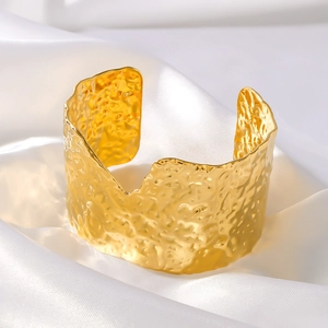 French vintage wide gold metal cuff bracelet with textured lava finish on white silk