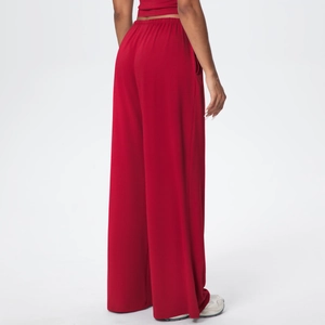 Macro detail of high-waist loose drawstring pants in red with soft draped fabric texture