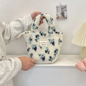 Detail of cute white plush tote bag with blue floral patterns and zip closure