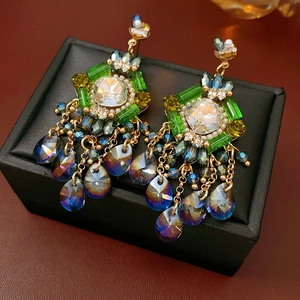 Detailed macro shot of vintage gold earrings with colorful gems and blue teardrop tassels