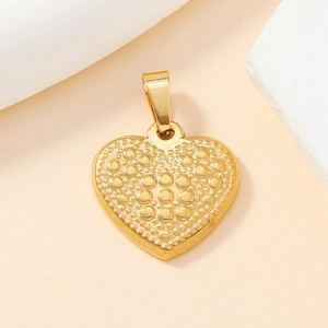 Close-up of golden heart pendant with embossed dot pattern and polished metal finish