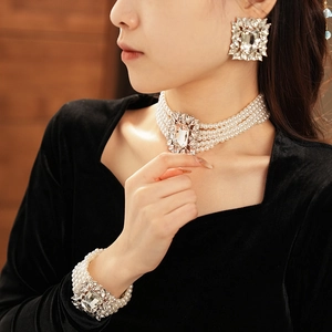 Close-up of layered pearl necklace and rhinestone earrings set on female model
