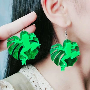 Vibrant green frog and monstera leaf acrylic drop earrings worn on model for fashion
