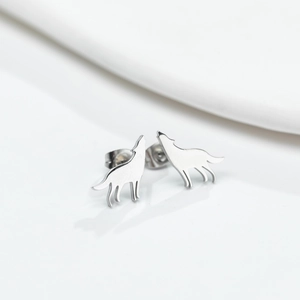Macro shot of polished silver wolf earrings with minimalist howling silhouette design