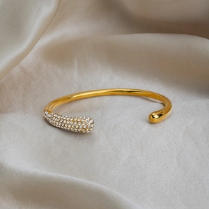 Detail view of 18K gold plated open bangle with micro-pave crystals on champagne silk