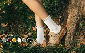 Detail of white women's crew socks with stylish rolled hem and ribbed knit texture