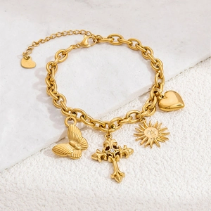 Macro detail of 18K gold plated bracelet featuring butterfly, cross, sun, and heart charms