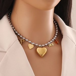 Close-up of dual-tone beaded necklace with gold heart, bow, and DIOS letter charms on model