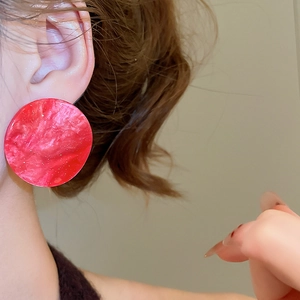 Close-up of oversized red marble acrylic round earrings with shimmering pearlescent effect